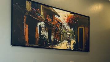 A hotel room with two beds, a large painting on the wall, and a bedside lamp.