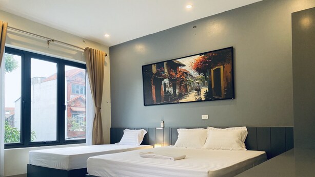 Una habitación de hotel moderna con una cama grande, una cama más pequeña y un cuadro en la pared.