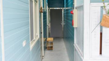 A narrow hallway with light blue siding, a wooden bench, and a door at the end.
