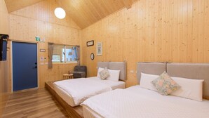 A wooden cabin with two beds, a small seating area, and a door with a window. - Little Lost B&B｜Family / Pet Friendly (Liuqiu)