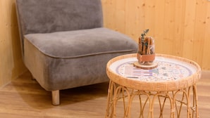 A grey upholstered chair and a wicker table with a decorative plate. - Little Lost B&B｜Family / Pet Friendly (Liuqiu)