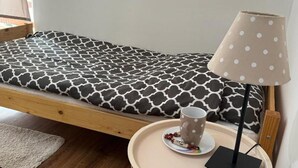 A single bed with a patterned mattress, a bedside table with a lamp, and a cup and saucer on the table. - Stunning home in Rybical with WiFi (Rybical)