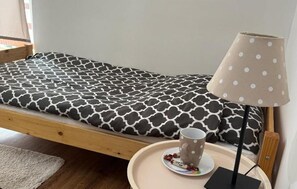 A single bed with a patterned mattress, a bedside table with a lamp, and a cup and saucer on the table. - Stunning home in Rybical with WiFi (Rybical)