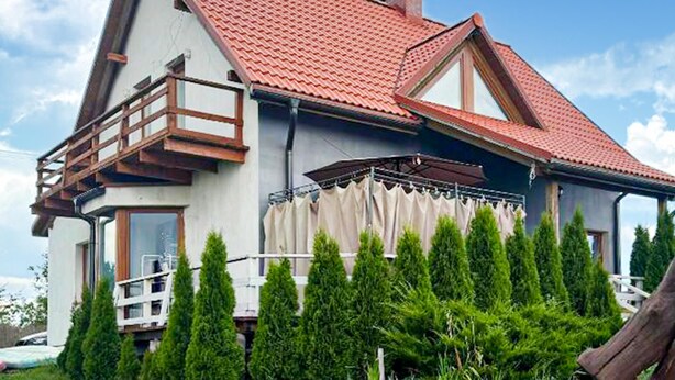 A two-story house with a red-tiled roof, a balcony, and a covered porch. - Stunning home in Rybical with WiFi (Rybical)