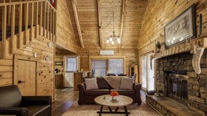 A cozy log cabin interior with a fireplace, a sofa, and a dining area. - Pool! View~Air Hockey~Fire Pit~Hot Tub~SemiSeclude (Sevierville)