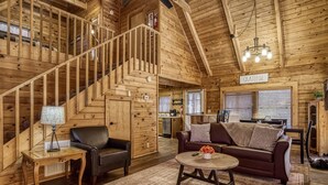 A wooden interior with a staircase, a sofa, a coffee table, and a sign that reads "GRATEFUL". - Pool! View~Air Hockey~Fire Pit~Hot Tub~SemiSeclude (Sevierville)