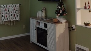 A living room with a fireplace, a television mounted on the wall, and a small Christmas tree.
