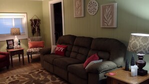 A cozy living room with a brown sofa, red armchairs, and a patterned rug.