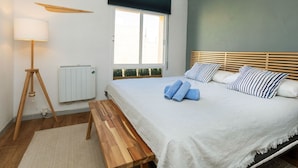 A bedroom with a wooden bed, a standing lamp, a window with blinds, and a ceiling fan. - Pescadors by Interhome (Alcanar)