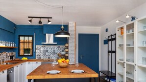 A modern kitchen with a wooden island, black bar stools, and a blue accent wall. - Pescadors by Interhome (Alcanar)
