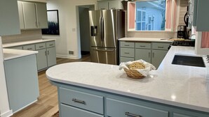 Una cocina moderna con armarios azul claro, electrodomésticos de acero inoxidable y encimera de mármol.