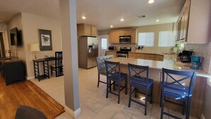 A modern kitchen with a central island, bar stools, and built-in appliances. - Family Fun Home (Beverly Hills)