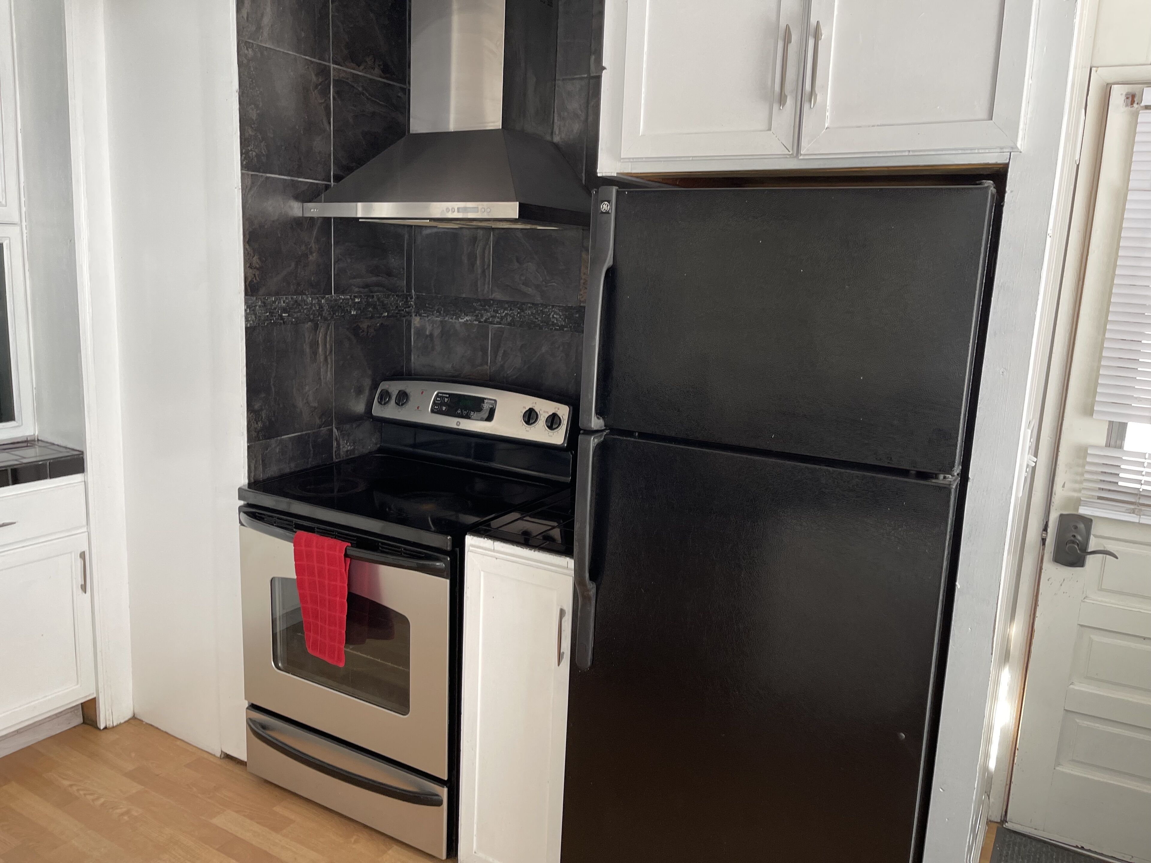A kitchen with a stainless steel stove, a black refrigerator, and white cabinets.