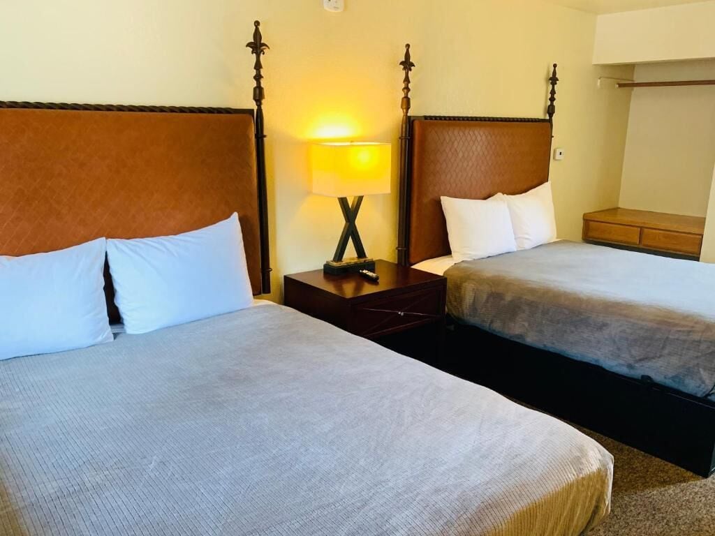 Ein Hotelzimmer mit zwei Betten, einem Nachttisch mit Lampe und einem Kleiderschrank.