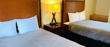 Ein Hotelzimmer mit zwei Betten, einem Nachttisch mit Lampe und einem Kleiderschrank.