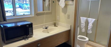 A bathroom with a white sink, a mirror, a toilet, and a shower area.