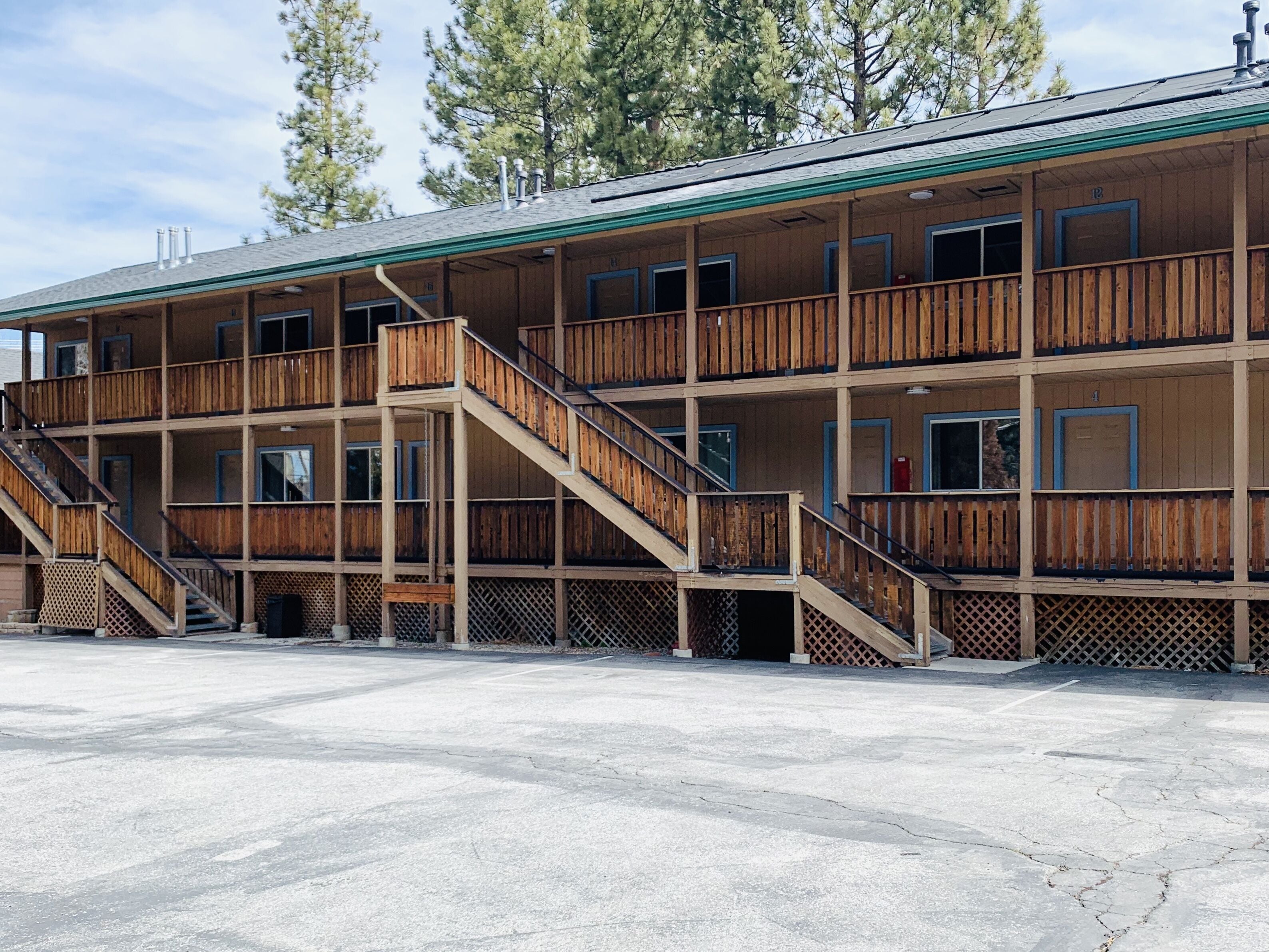Un edificio in legno a più piani con balconi, scale e un'area di parcheggio coperta.