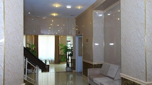 A lobby with marble walls, a staircase, a reception desk, and a sofa. - ATS Hotel Hoan Kiem - by Bay Luxury (Hanoi)