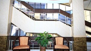A lobby with a marble staircase, two upholstered chairs, and a potted plant. - ATS Hotel Hoan Kiem - by Bay Luxury (Hanoi)