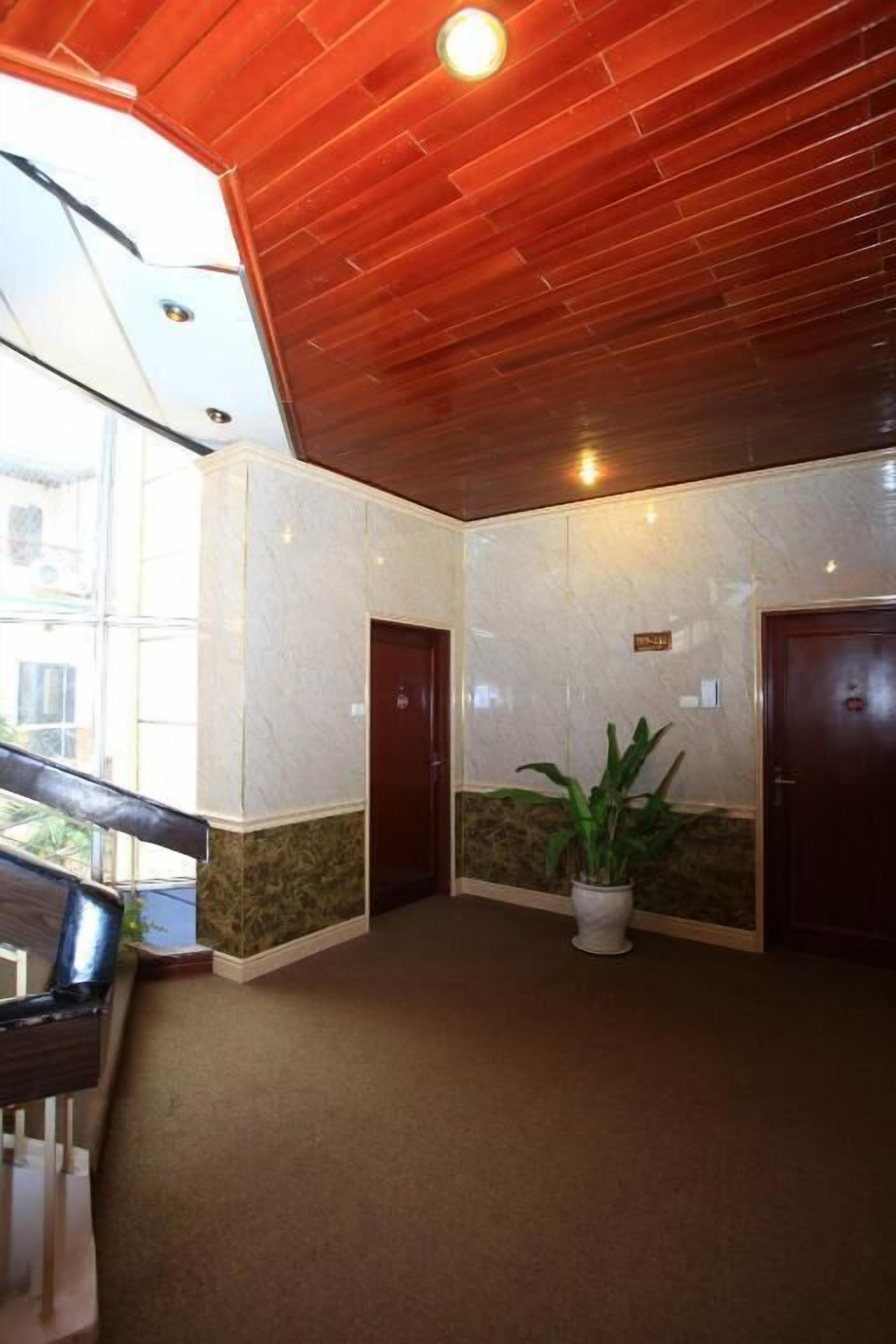 Eine Lobby mit Holzboden, Marmorwänden, einer Zimmerpflanze und einer Treppe.