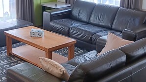 En moderne stue med en sort lædersofa, et træsofabord og et fladskærms-tv monteret på væggen.