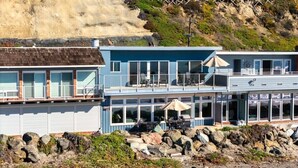 A coastal building with a balcony, outdoor seating, and a view of the beach. - Beachfront Rio Del Mar Home - 5 bedrooms! (Aptos)