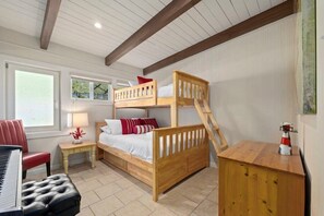 A room with a bunk bed, a piano, a red chair, a nightstand with a lamp, and a small cabinet. - Beachfront Rio Del Mar Home - 5 bedrooms! (Aptos)