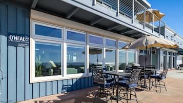 En restaurang vid havet med uteservering och stora fönster med utsikt över havet.