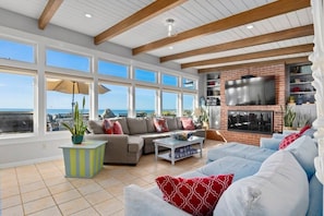 A spacious living room with a large TV, comfortable seating, and a view of the ocean. - Beachfront Rio Del Mar Home - 5 bedrooms! (Aptos)
