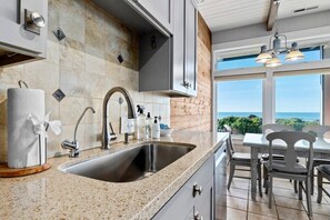 A kitchen with a granite countertop, stainless steel sink, and modern cabinetry.