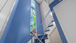A staircase with a blue wall and a stained glass window.