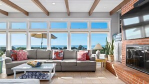 A spacious living room with a large window, a sofa set, a coffee table, and a fireplace. - Beachfront Rio Del Mar Home - 5 bedrooms! (Aptos)