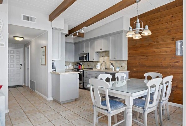 Une cuisine moderne avec des meubles blancs, un îlot central et un coin repas avec des chaises blanches.