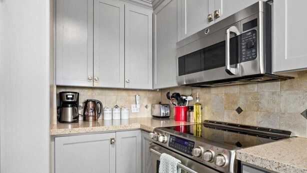 A modern kitchen with stainless steel appliances, including a microwave, oven, and coffee maker. - Beachfront Rio Del Mar Home - 5 bedrooms! (Aptos)