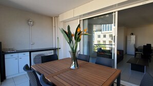 A modern kitchen with white cabinets, a built-in oven, and a dining area with a wooden table and chairs. - Port-Fréjus, Cesaree Borghèse, 2/3 rooms 52m2, 4 beds, swimming pool, air-conditioned, parking, close access to the beach, large balcony for a pleasant stay in the sun, relaxation and leisure (Fréjus)