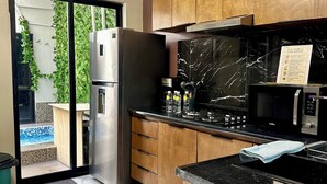 A modern kitchen with wooden cabinets, a stainless steel refrigerator, a black countertop, and a view of a swimming pool through glass doors. - Casa a tan Solo 5 Minutos de la Plaza Principal! Ideal Para Familia y Amigos (Tequila)