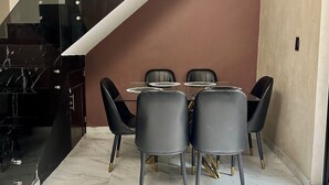 A modern dining area with a marble floor, a wooden table, and black chairs with gold accents. - Casa a tan Solo 5 Minutos de la Plaza Principal! Ideal Para Familia y Amigos (Tequila)