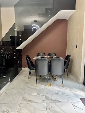 A modern dining area with a marble floor, a wooden dining table, and black chairs with gold accents. - Casa a tan Solo 5 Minutos de la Plaza Principal! Ideal Para Familia y Amigos (Tequila)