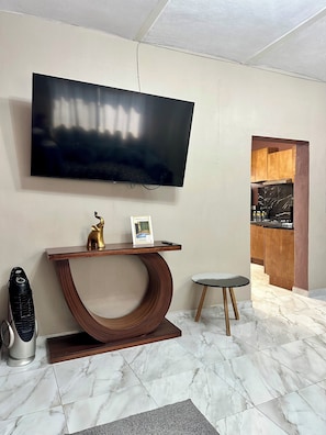 A modern living room with a large flat-screen TV, a wooden console table, a small round table, and a marble-tiled floor. - Casa a tan Solo 5 Minutos de la Plaza Principal! Ideal Para Familia y Amigos (Tequila)