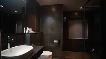 A modern bathroom with a large sink, toilet, and glass shower enclosure.