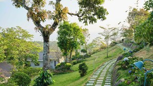 A garden pathway with stone steps, surrounded by lush greenery and trees. - Blanket Days Resort and Spa (Peermade)