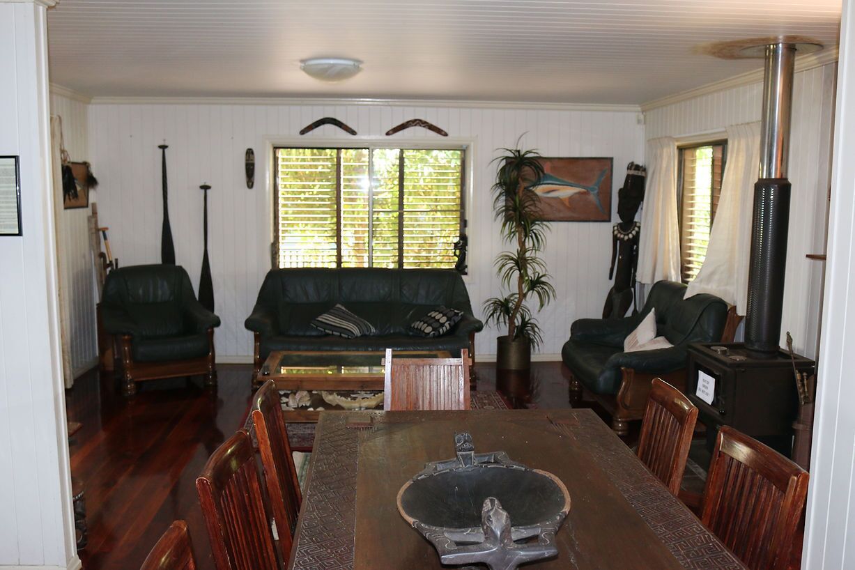 A dining room with a wooden table, chairs, a sofa, and a fireplace.