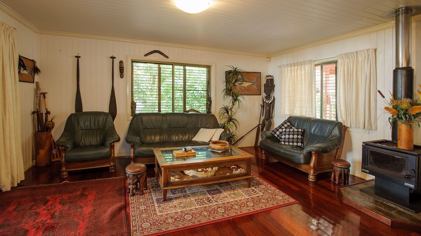 A living room with a leather sofa, a coffee table, and a wood-burning stove.