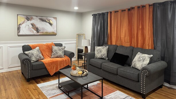 Ein Wohnzimmer mit zwei grauen Sofas, einem Couchtisch und Holzboden.