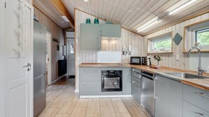 A modern kitchen with wooden cabinets, stainless steel appliances, and a window providing natural light.