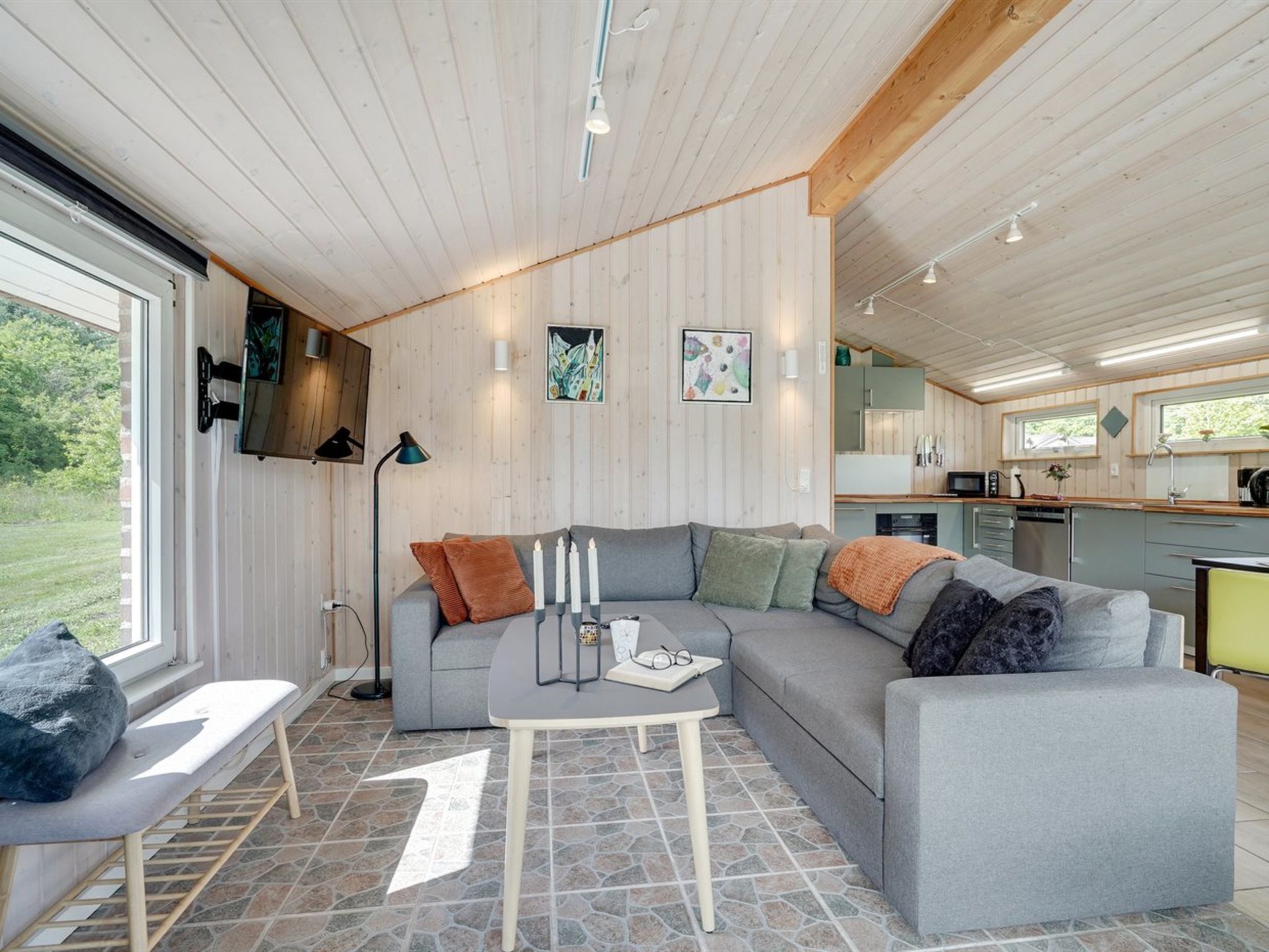 A modern living room with a grey sectional sofa, a small table with candles, and a bench.
