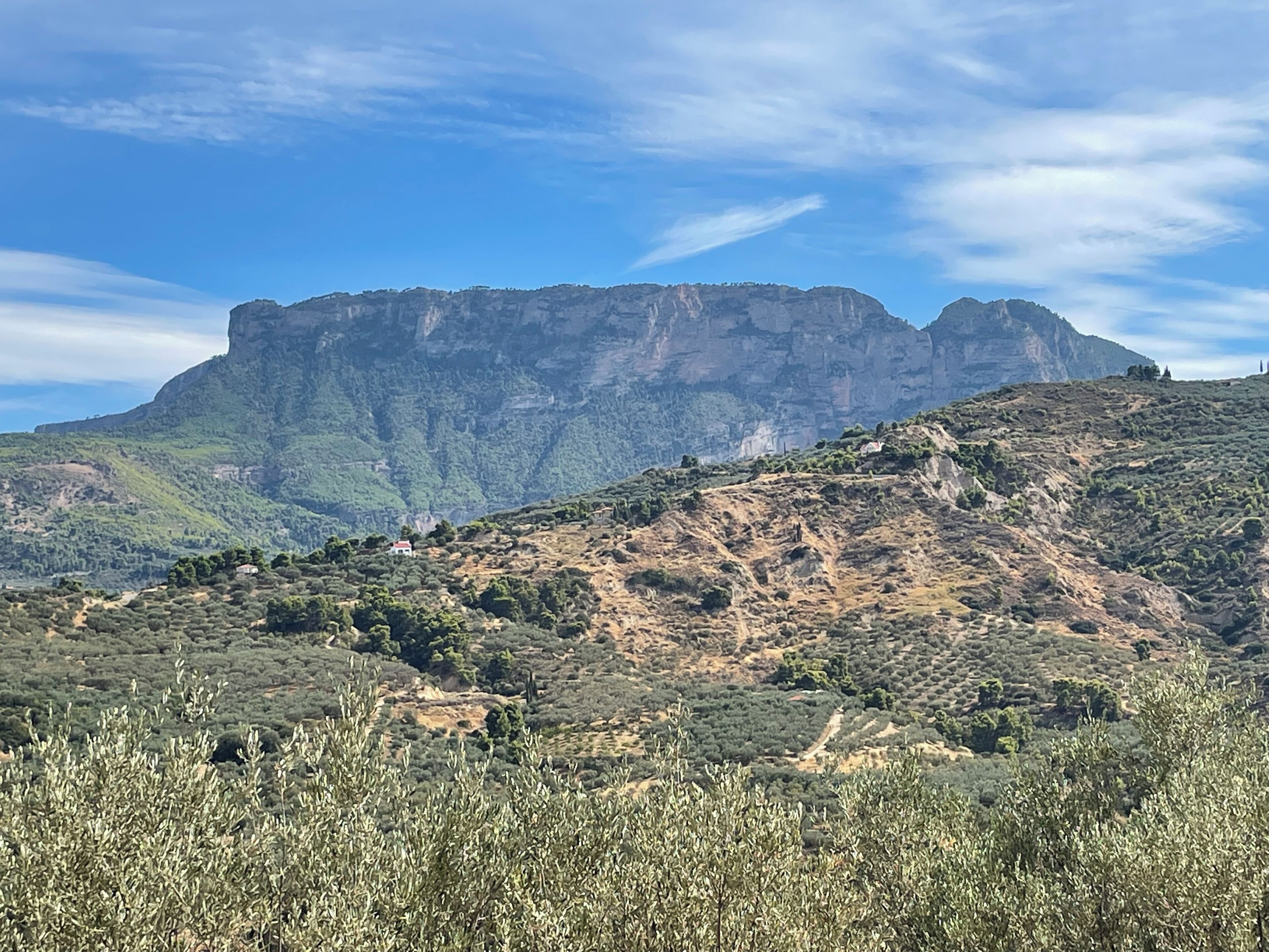 Paisagem montanhosa com um pico rochoso imponente e vegetação escassa.