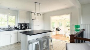 Una cocina moderna con armarios blancos, una encimera negra y dos taburetes de bar.