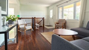 Una sala de estar moderna con una escalera de madera, una mesa de centro redonda y un sofá gris.