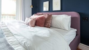 Un dormitorio con una cama, una ventana y dos cuadros en la pared.